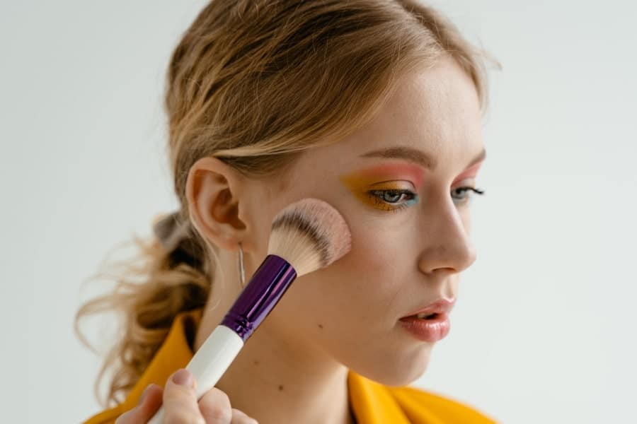 woman applying blush for beauty boost