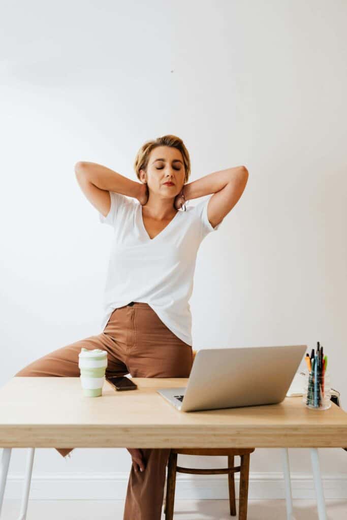 Woman standing at her desk balancing on one leg in a yoga pose, showing how movement can help recharge energy levels.