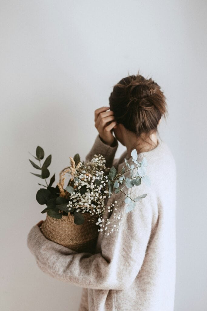 woman holding plant and flowers to relieve stress