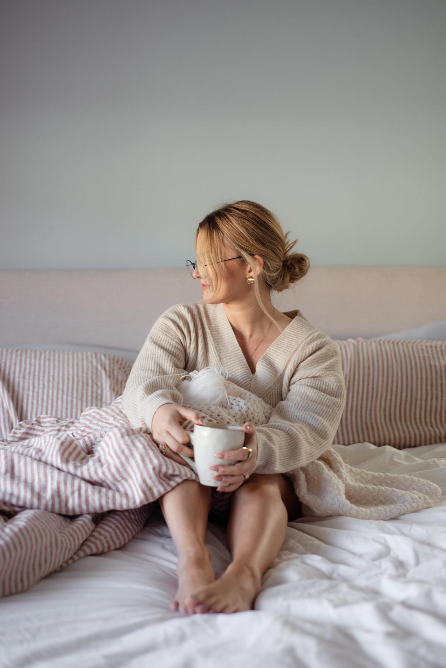 A woman starting her self-care Saturday with coffee in bed, enjoying a slow morning.