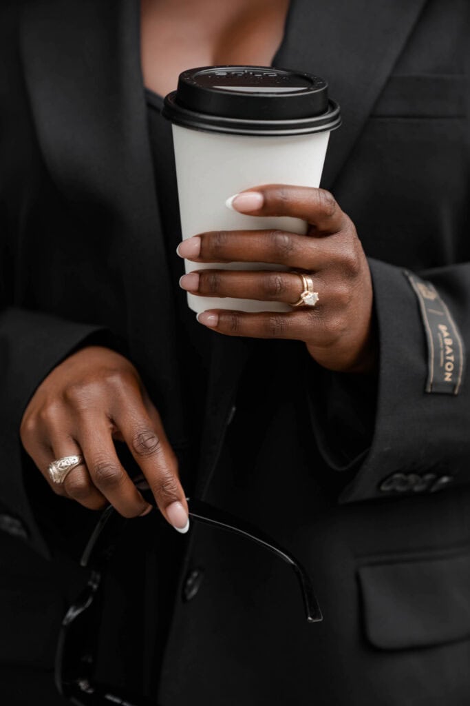 A close-up of a woman holding a to-go coffee cup, representing a small, intentional treat for self-care.