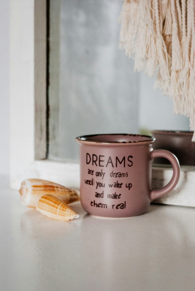 Mug on a dresser with the quote "Dreams are only dreams until you wake up and make them real," representing daily affirmations.